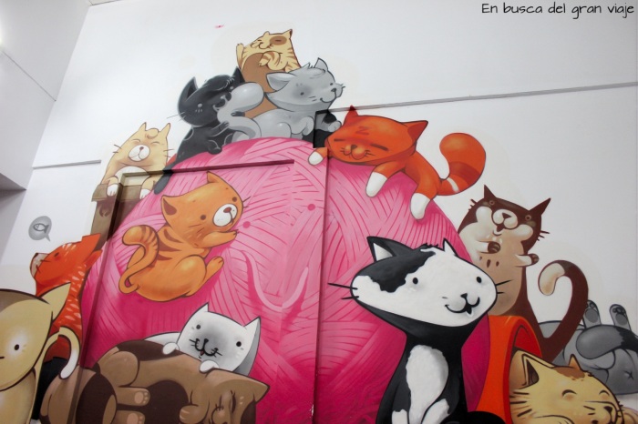 Un mural pintado de un montón de gatos jugando con un ovillo de ñana
